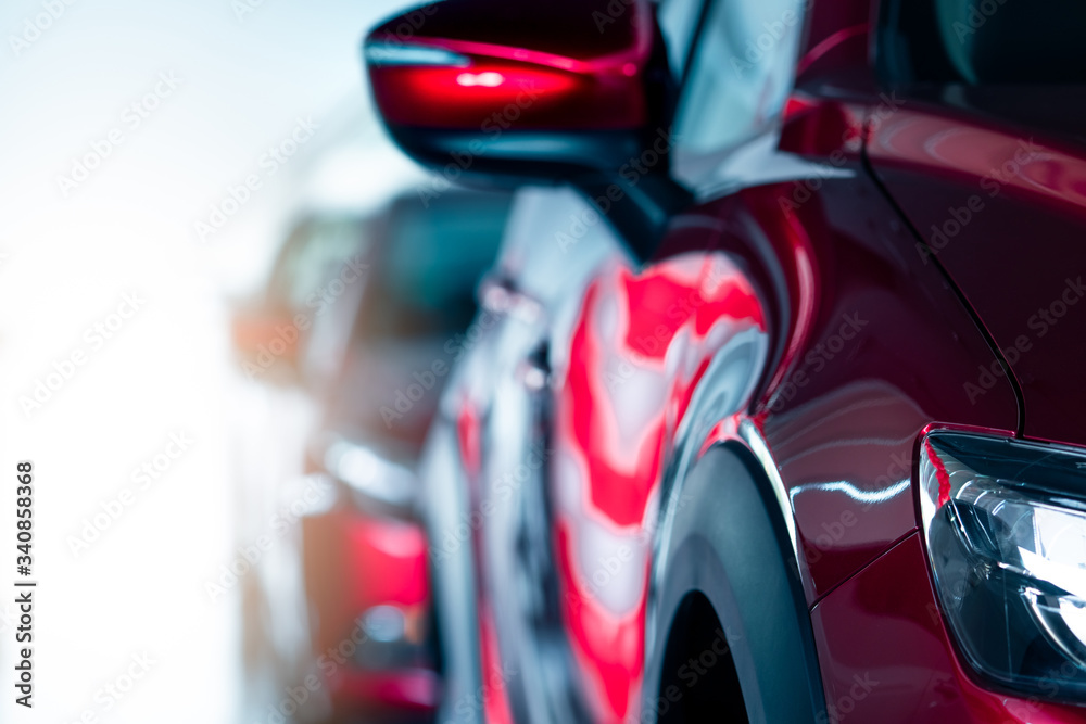 Closeup headlamp of red car parked in modern showroom. New and luxury car. Car dealership concept. Automotive industry. Automobile leasing. Front view of red shiny car parked in a row in showroom. Closeup headlamp of red car parked in modern showroom. New and luxury car. Car dealership concept. Automotive industry. Automobile leasing. Front view of red shiny car parked in a row in showroom.