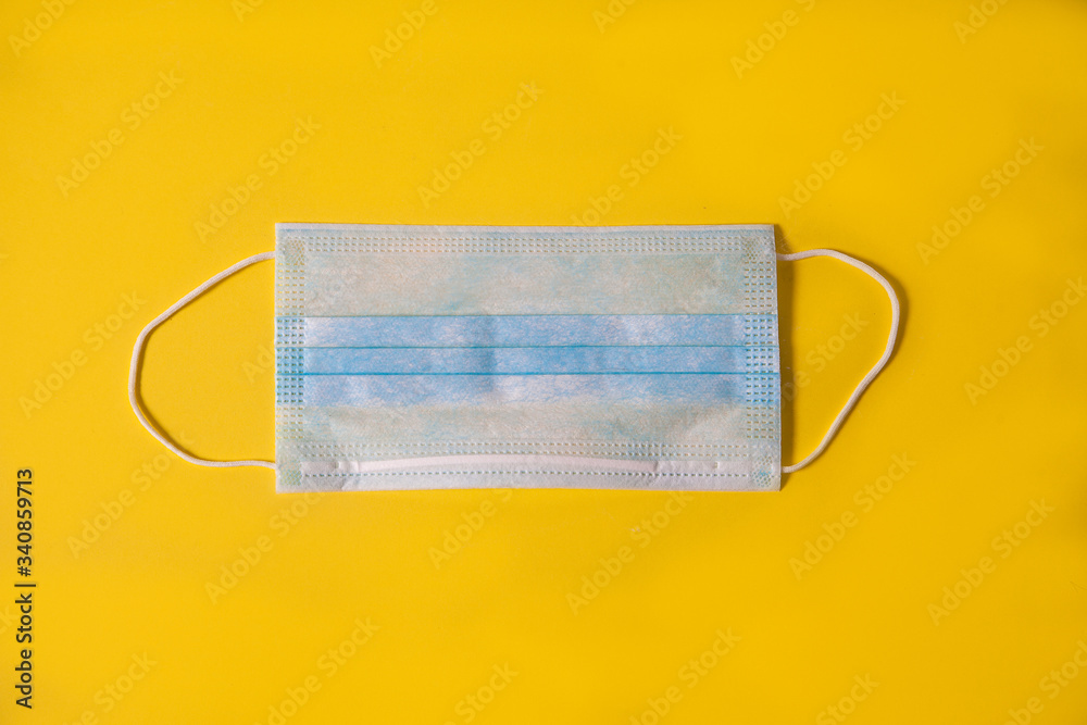 Medical mask on yellow background flat lay top view with copy space. Protection against virus, coronavirus, flu, colds, diseases. Traditional medical tool, concept of health. Medical background Medical mask on yellow background flat lay top view with copy space. Protection against virus, coronavirus, flu, colds, diseases. Traditional medical tool, concept of health. Medical background