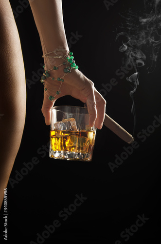Canvas Print Caucasian model holds glass of whiskey with icecubes and smoking cigar in her ha