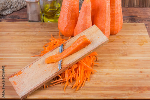 Carrot during shredding on grater for Korean carrot salad prepare photo