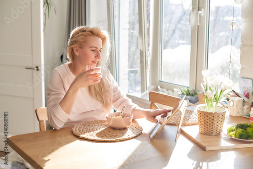 Middle-aged woman using tablet in kitchen