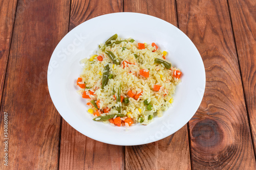Rice boiled with vegetables on white dish on rustic table