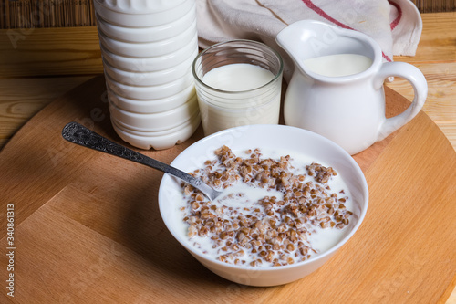 Buckwheat porridge with milk against dairy products lit on right