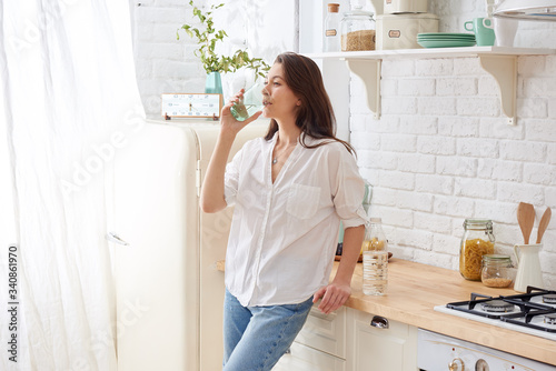 Gorgeous woman drinking water in her kitchen