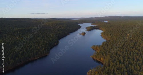 Lake Sotkajarvi in Lapland, Aerial, descending, drone shot, towards a river, in middle of arctic forest and polar nature, sunny autumn evening, in Lemmenjoki national park, Inari, Finland photo