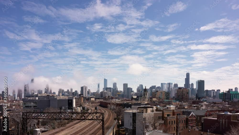 Fog flowing though the Chicago skyline with partly cloudy skies on the first day of April