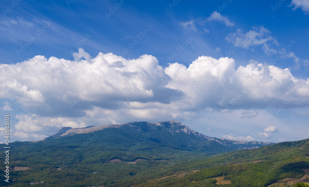 Sky with clouds over mountain with slopes covered with forests Sky with clouds over mountain with slopes covered with forests
