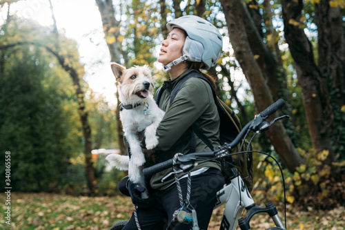 19/4/2020 Asian woman with a bike talking with a dog in autumn at the Botanic garden, Oamaru, New Zealand. Concept about exercise while social isolation from Coronavirus or Covid 19. With copy space.