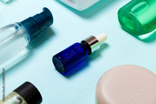 Top view of cosmetic products in different jars and bottles on blue background. Close-up of containers with copy space