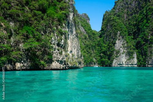 Beautiful turquoise green Pileh Lagoon water with a small white boat in the middle surrounded by steep limestone hills at Phi Phi Island archipelago, Krabi province, Thailand. © Lisa