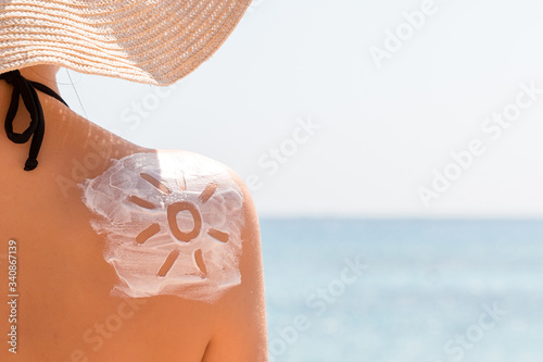 Sunscreen lotion in sun shape on tanned woman's shoulder