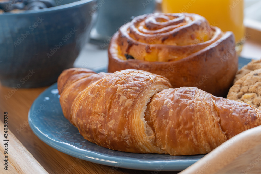 Breakfast served in bed on wooden tray with coffee and croissants. Breakfast in bed close up.
