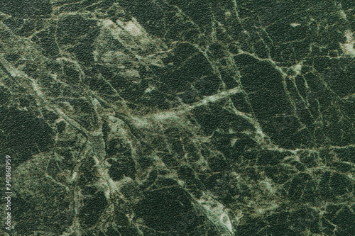 Texture of dark green marble for tabletop with olive lines of a pattern, macro background. Artificial stone countertop.