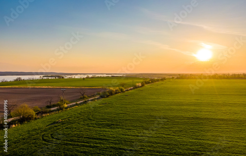 Aerial view of agriculture land at Palava hills  Czech republic. Rural scene near vineyards with power line above dirty road. Summer weather  sunset time. Nove mlyny water lake in background.