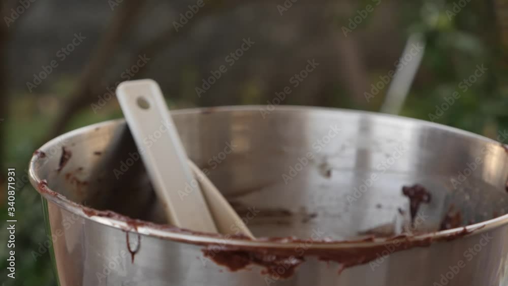 Women tossing spatulas into a mixing bowl that has rests of brownie mix Women tossing spatulas into a mixing bowl that has rests of brownie mix