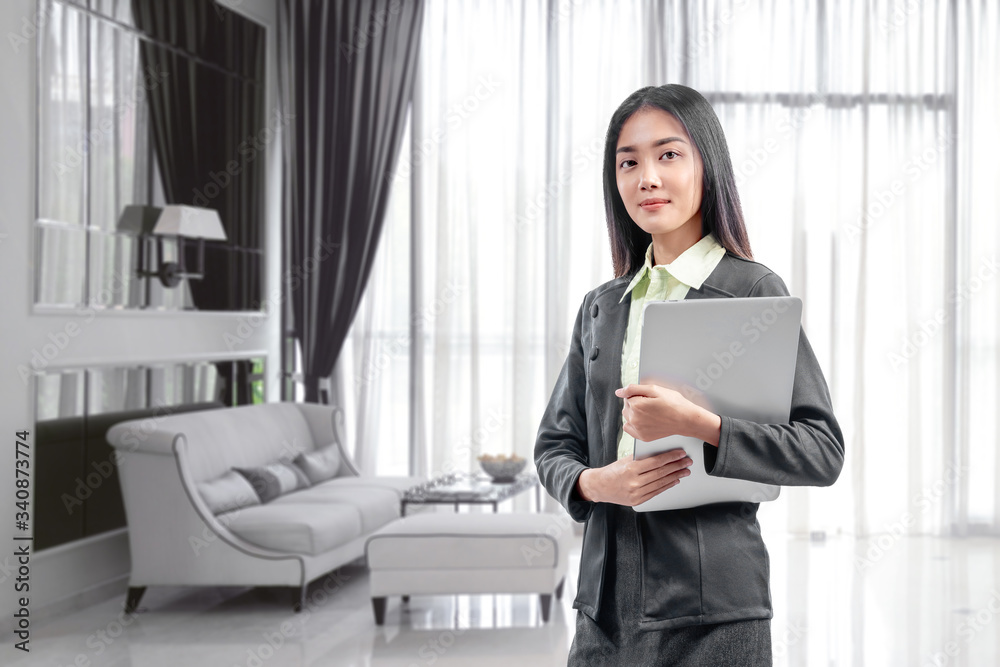 Asian businesswoman standing while carrying the laptop working from home Asian businesswoman standing while carrying the laptop working from home