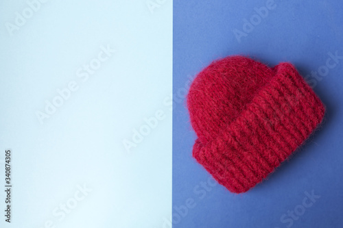 Knitted red hat on the two colors background. Blue background. Knitting courses. Online education. Place for text and design. Copy space. Knitting with love. Quarantine life. Flat lay. Top view. Place
