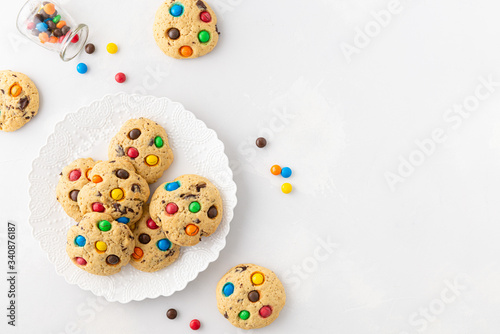 Cookies with colourful candy chips on white background. Top view, copy space. Bakery, recipe, confectionery, cookbook