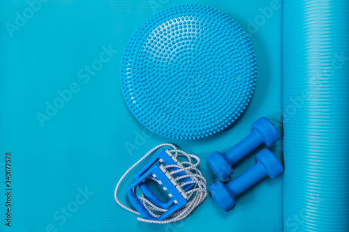 Fitness concept - blue dumbbells, expander and massage cushion on yoga mat