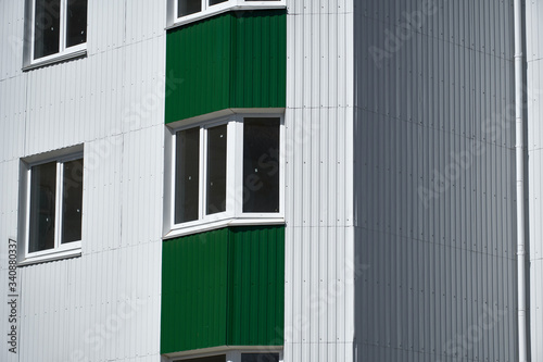 facade of a new multistory building with white and green metal siding, many Windows