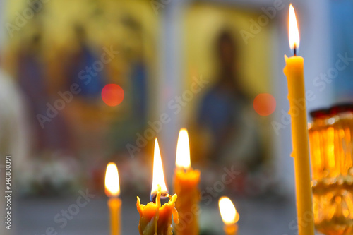 Candles are lit on the background of icons of the Orthodox Church. Blurred long-range plan. The concept of Orthodox faith.