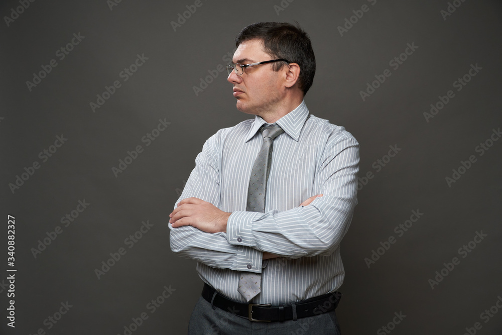 a man dressed as a businessman posing in a studio on a gray background, glasses, a light striped shirt and tie - casual office wear