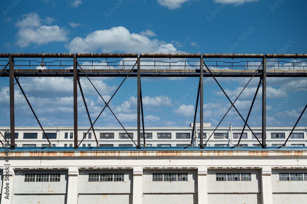 An old rusty metal walkway above an old white building with windows