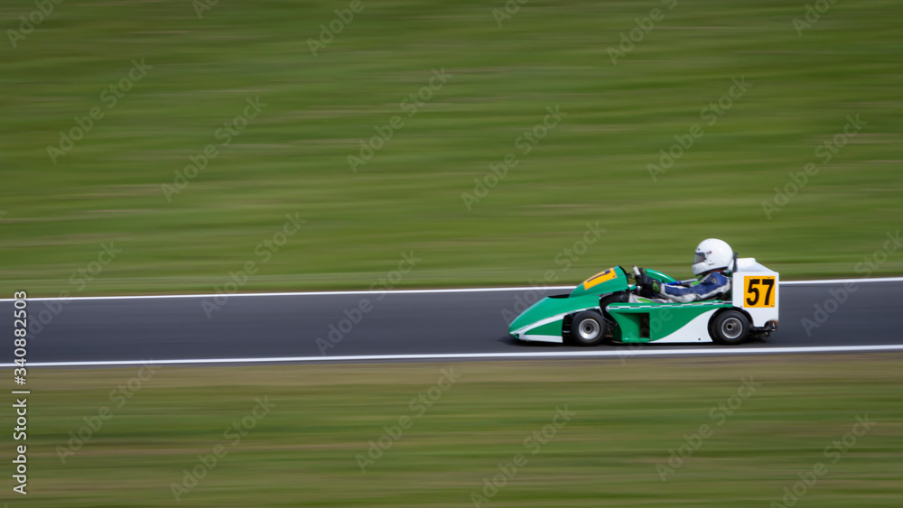 A panning shot of a green and white racing go-kart.