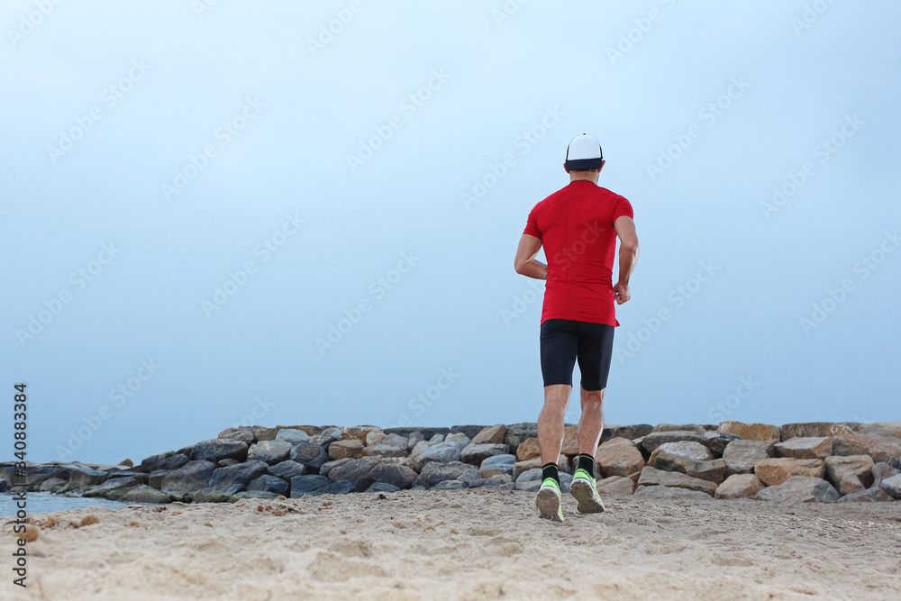 Beach training. Beach runner. A young athletic attractive man runs alone by the sea.