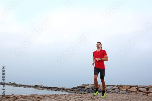 Run on the beach. A young athletic attractive man runs alone by the sea.