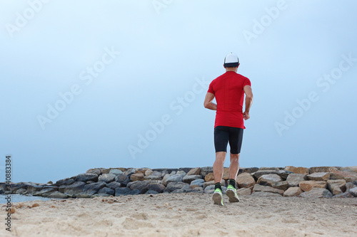 Beach training. Beach runner. A young athletic attractive man runs alone by the sea.