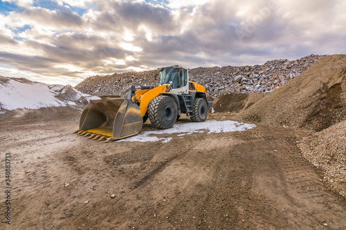 Excavator in a quarry extracting and moving stone for its transformation
