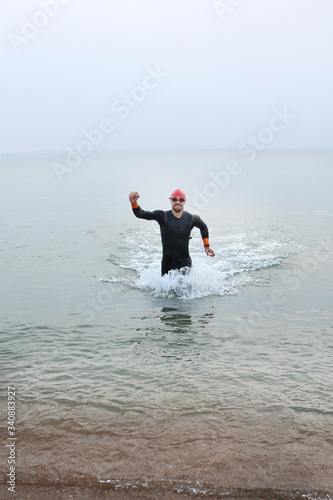 Swimming in the sea, a man swims. The man in thermal foam does water sports in the sea.