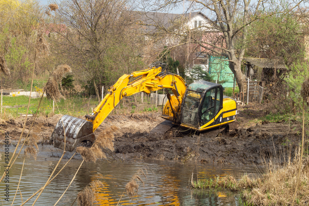 Crawler excavator or digger dredges on the lake Crawler excavator or digger dredges on the lake
