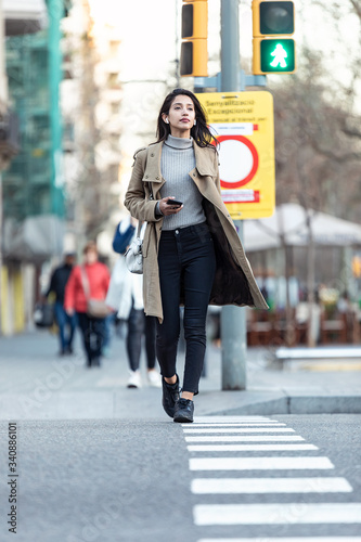 Pretty young woman crossing the street while listen to music with the wireless earphones. © nenetus