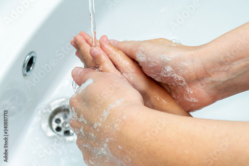 woman helps children wash hands under the tap close-up