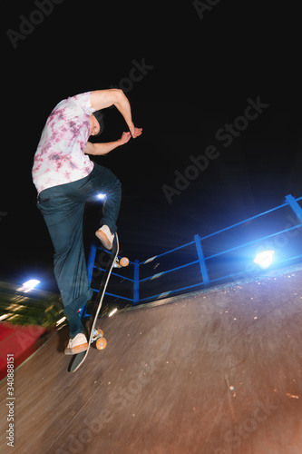 A young skater at night in a skatepark does the trick Ollie on ramp . X-ray culture nightlife concept