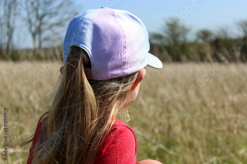 little girl in the field wearing a cap