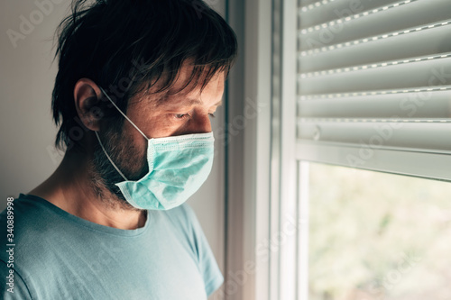 Depressed man with protective mask in self-isolation quarantine during virus outbreak pandemic