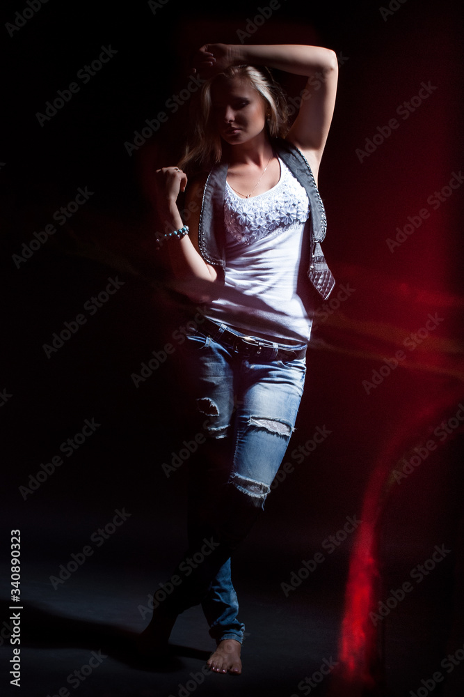 young, blonde girl in jeans clothes on a dark background