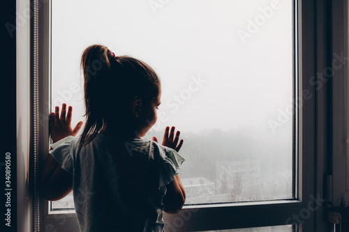 Billede på lærred Child looks out the window at smog in the city of Kiev