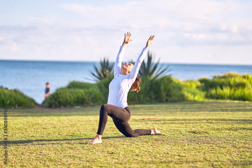 Young beautiful sportwoman practicing yoga. Coach teaching warrior pose at park Young beautiful sportwoman practicing yoga. Coach teaching warrior pose at park