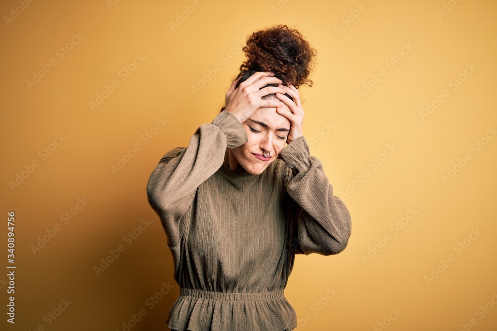 Young beautiful brunette woman with curly hair and piercing wearing casual dress suffering from headache desperate and stressed because pain and migraine. Hands on head. Young beautiful brunette woman with curly hair and piercing wearing casual dress suffering from headache desperate and stressed because pain and migraine. Hands on head.