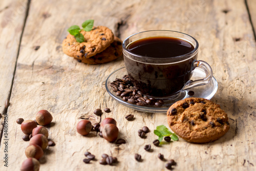 Black coffee in a glass cup with coffee beans. near cookies and hazelnuts