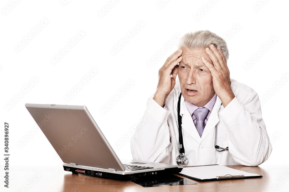 Elderly tired doctor with a laptop on white background Elderly tired doctor with a laptop on white background