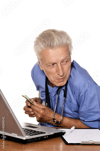 Medical doctor with money at work over white background