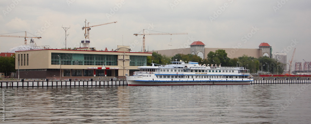 Moscow, Russia, White tourist boat Sergey Obraztsov near Pieron South Port on Moscow River water and Embankment background on cloudy Summer day