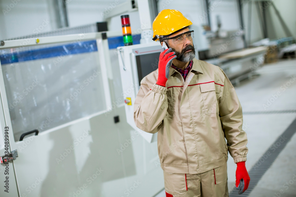 Mature industrial man engineer with smartphone in a factory Mature industrial man engineer with smartphone in a factory