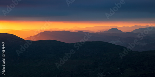 Panoramic view of mountainous landscape in the last lights of the day on the horizon and the cloudy and stormy sky.