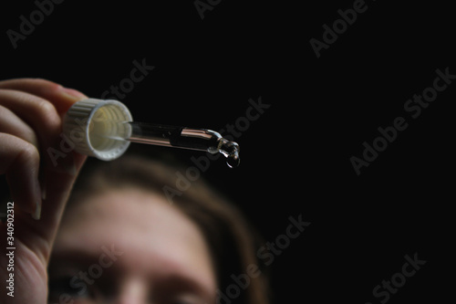 female with beautiful nails hold pipette isolated on black background